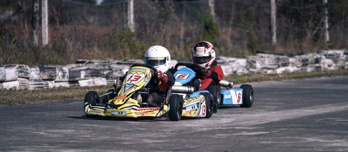 Free Two go-karts racing fiercely on an outdoor track showcasing speed and competition. Stock Photo