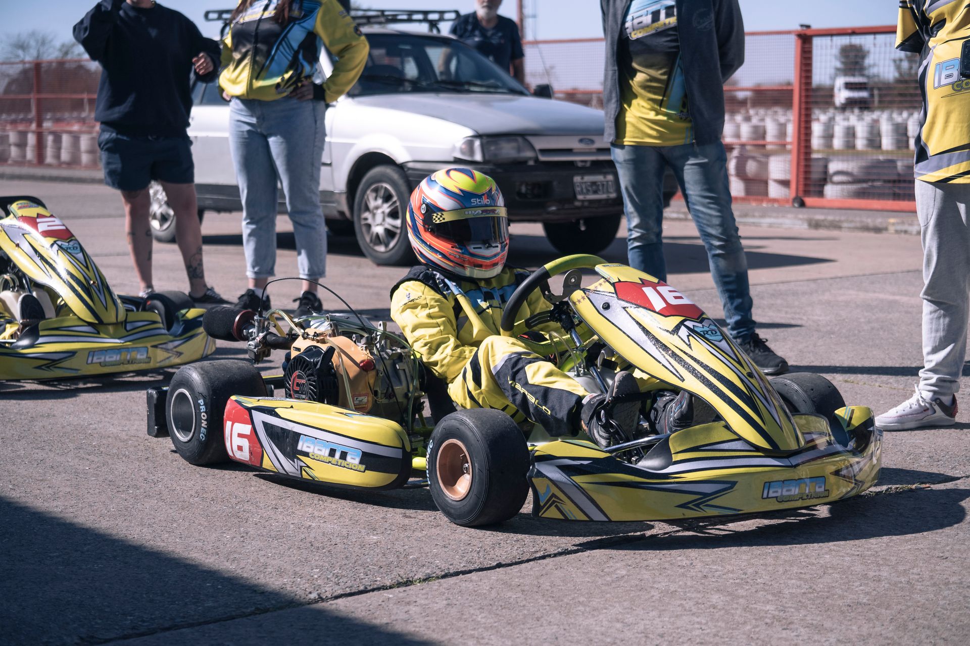 Driver in racing suit prepares for an intense go-kart competition on a sunny day