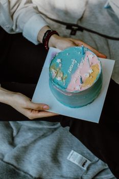 A vibrant birthday cake with colorful icing held in hands, perfect for celebrations.