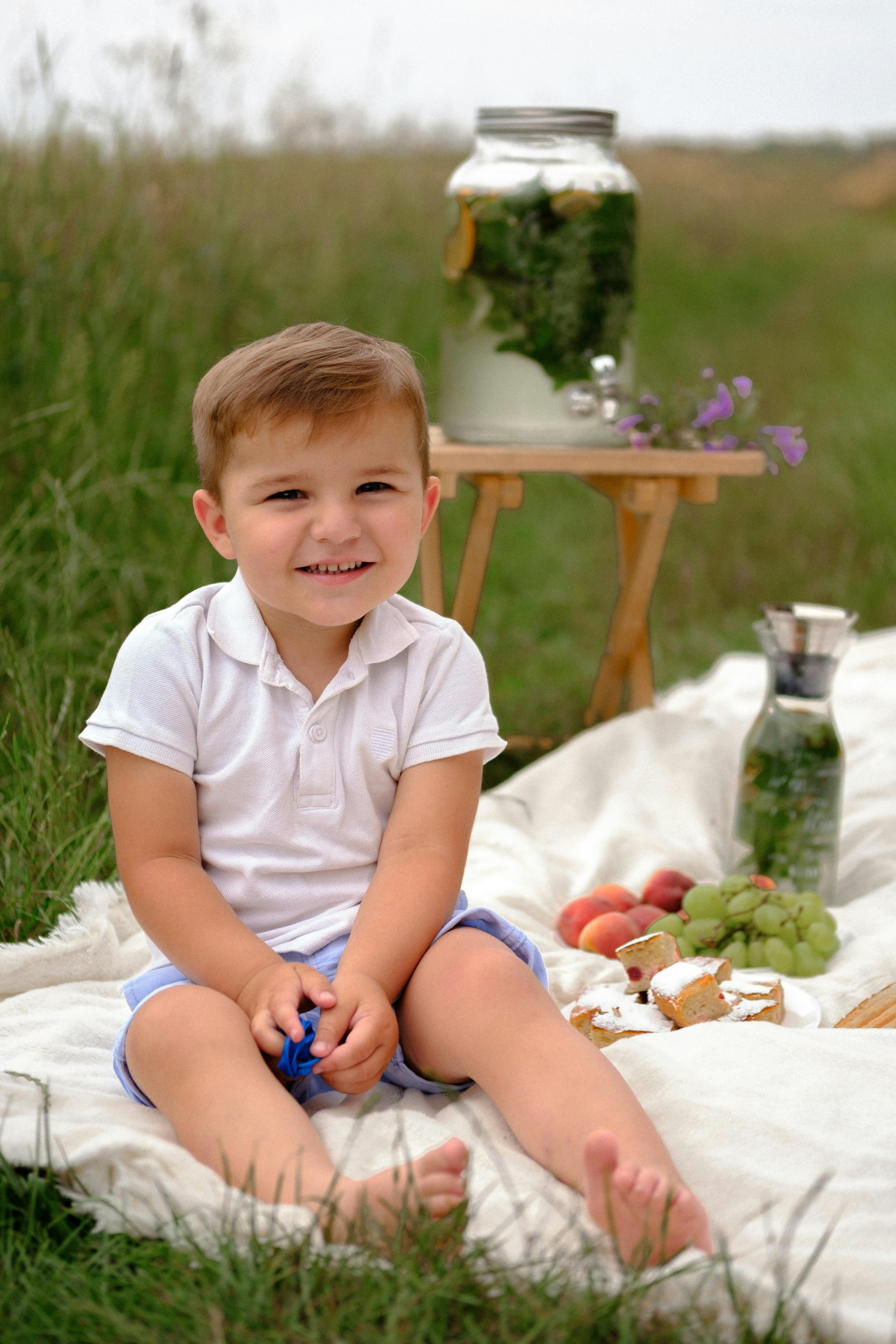 Photo of a Boy Sitting on a White Blanket around Green Grass · Free