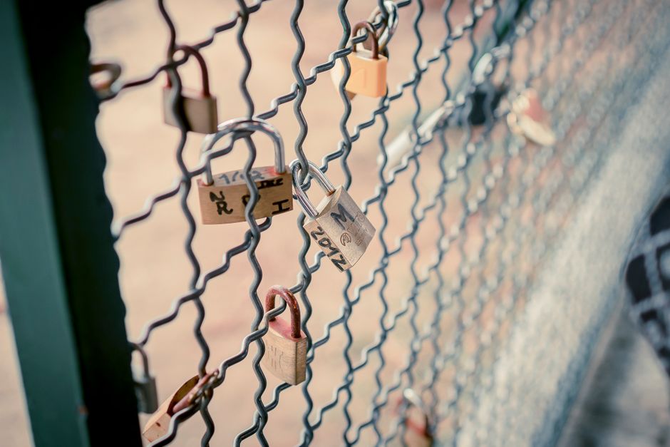 Romantic love locks attached to a chain link fence symbolize everlasting love and unity.