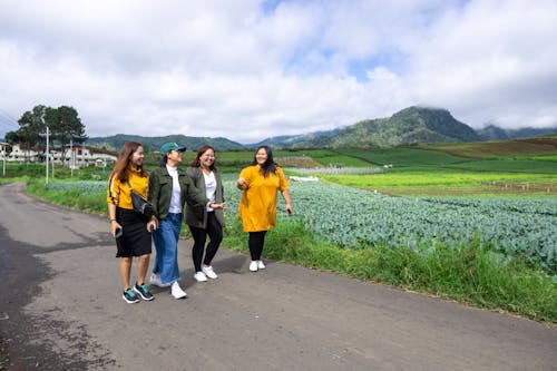 Friends Walking Together on a Road near a Farm Fields