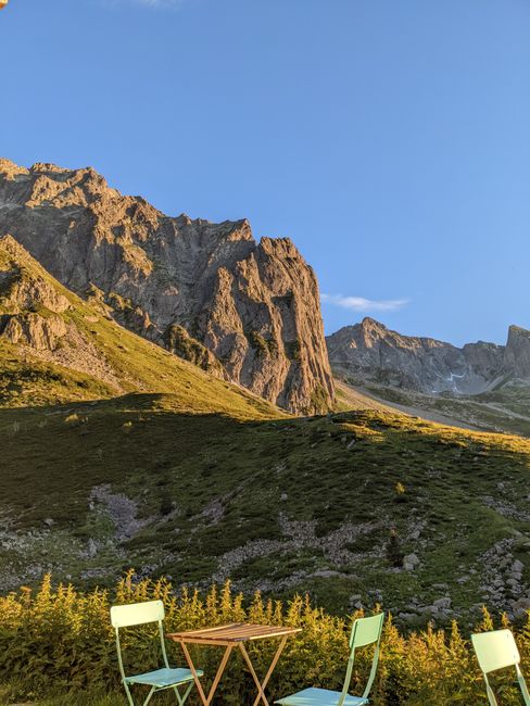 Serene mountain landscape with chairs and table under clear sky at sunset.