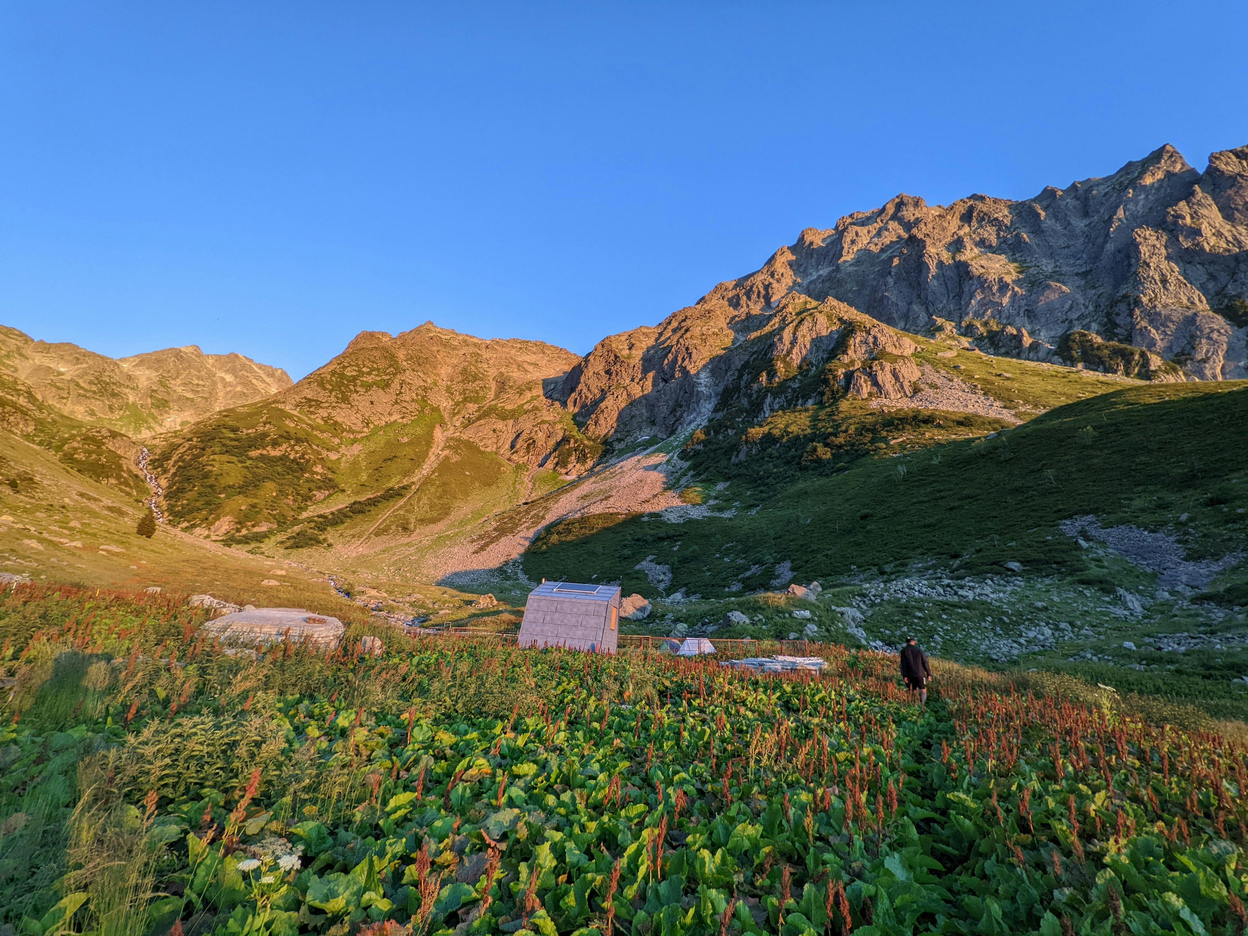 Beautiful mountain valley landscape at sunrise with lush vegetation and blue sky.