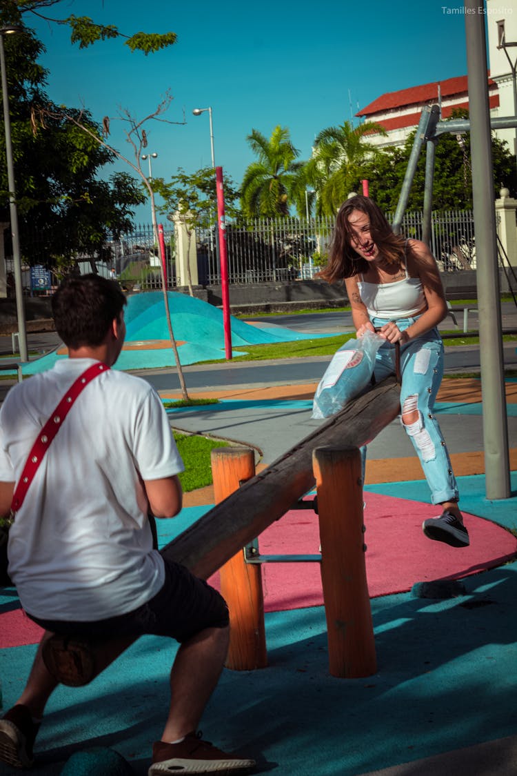 Boy And A Girl Playing On A Playground Seesaw