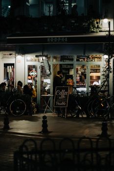 Warm and inviting café scene at night with customers and bicycles outdoor.