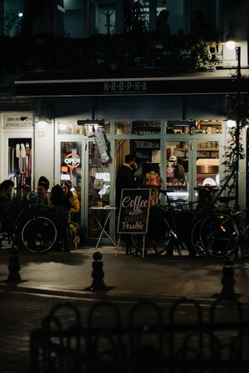 Free Warm and inviting café scene at night with customers and bicycles outdoor. Stock Photo
