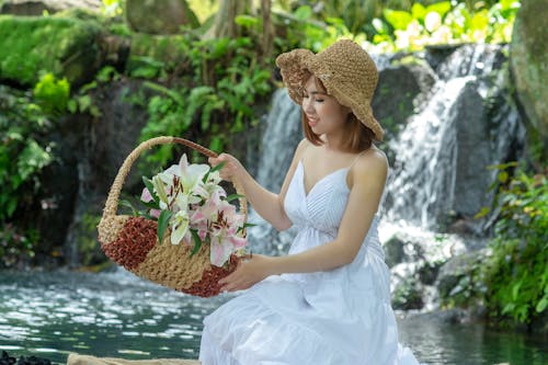 Женщина держит корзину, сидя возле водопада