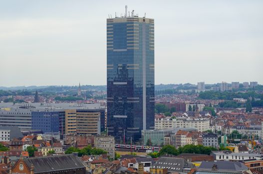 Aerial view of a modern skyscraper amidst Brussels city skyline.