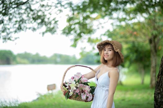 Young woman enjoying a day outdoors with a basket of flowers, exuding joy and beauty.