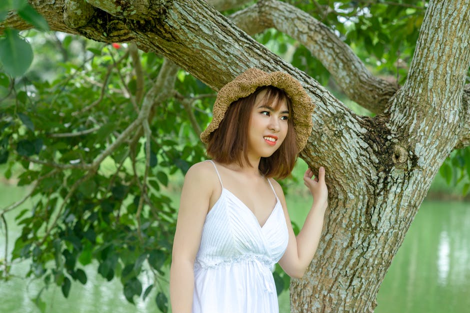 Woman Wearing Brown Hat Standing Under Green Tree.