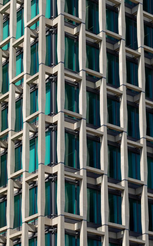 Free Close-up of a contemporary skyscraper facade with geometric patterns and blue glass windows. Stock Photo