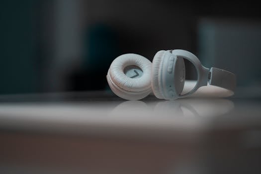 Close-up view of white headphones on a reflective surface, showcasing modern audio technology.