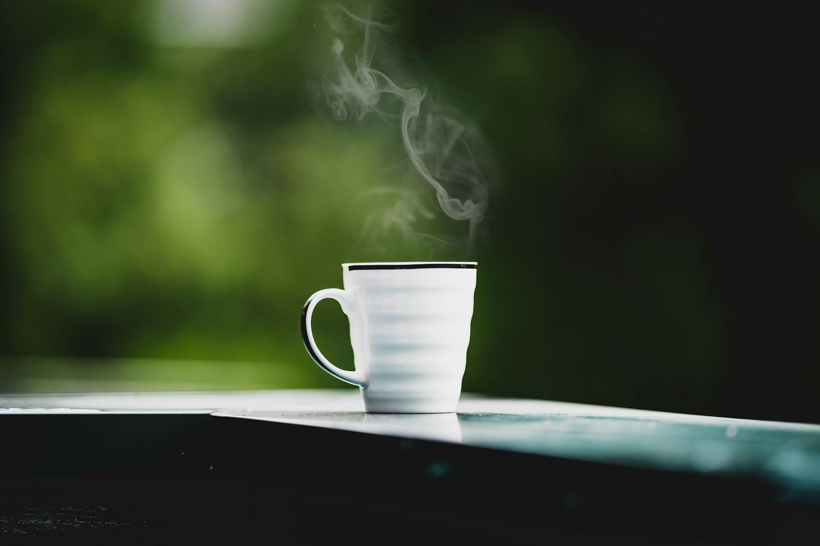 Steaming coffee mug on a table with soft green background
