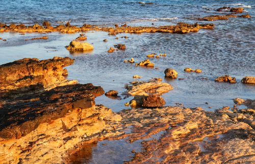 Free Sunlit coastal landscape with eroded rocks and serene sea view, perfect for nature themes. Stock Photo