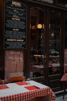 Charming entrance of a Parisian restaurant showcasing a traditional French menu.