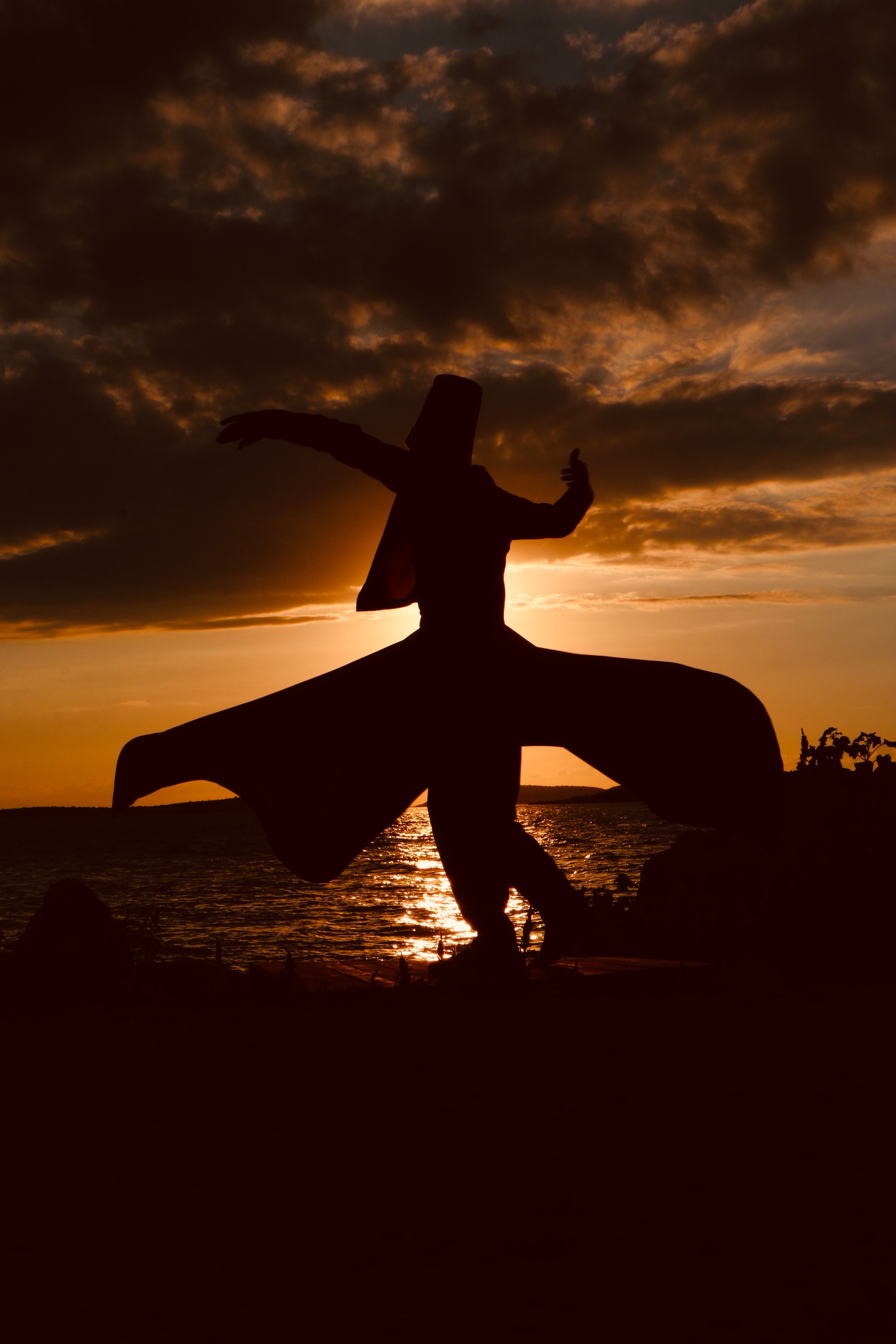 Silhouette of a Person Standing Near Body of Water During Sunset · Free ...