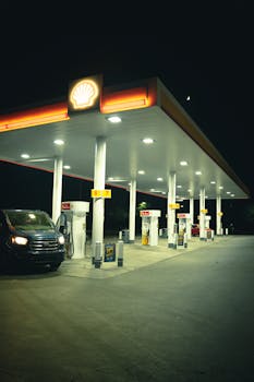 A gas station brightly lit at night with a parked car under neon lights.