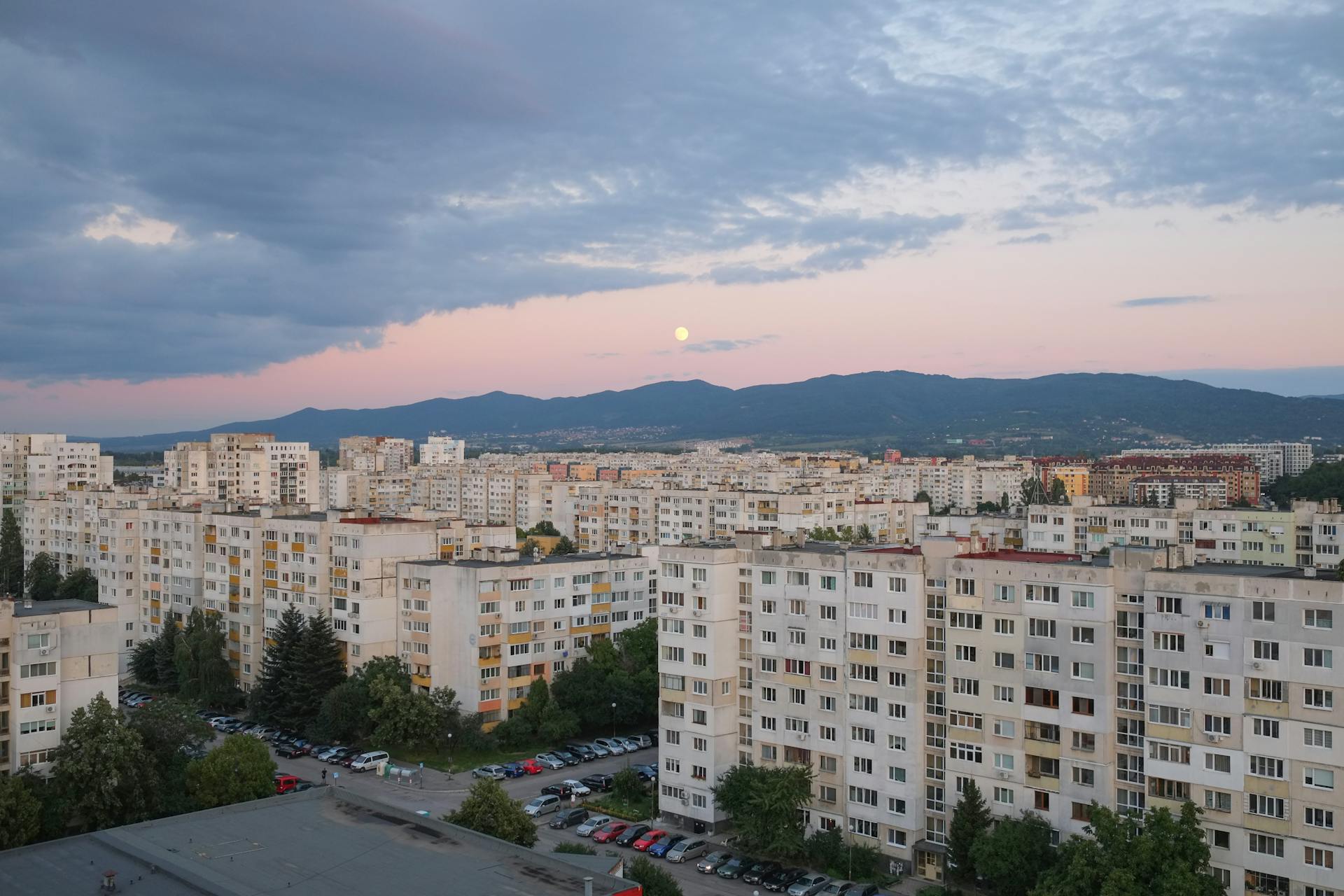Aerial shot of Sofia's residential area with sunset view and mountains in the background.