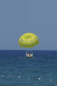 Experience the excitement of parasailing above the ocean with a vibrant yellow parachute.