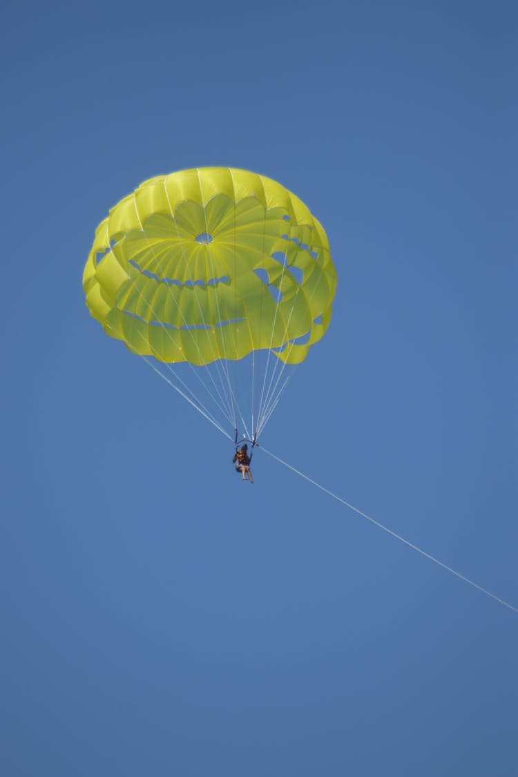 Person Parasailing Under A Clear Blue Sky