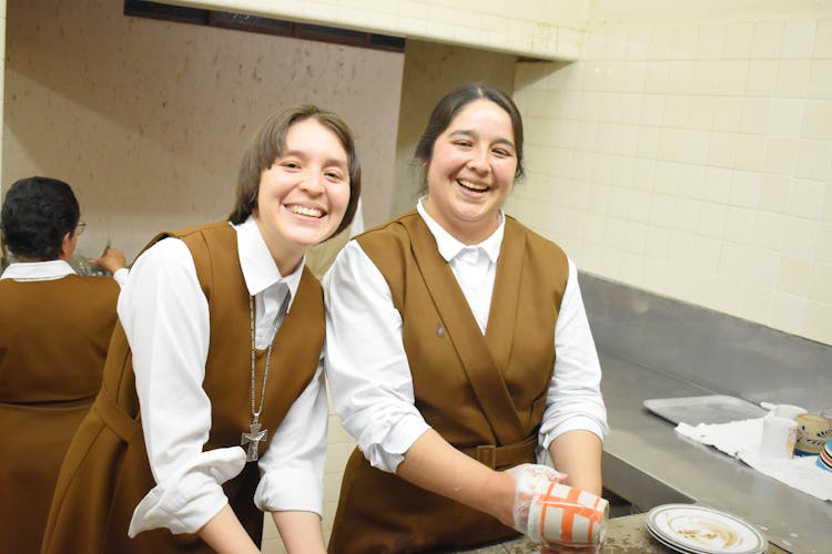 Women Smiling While Washing Dishes