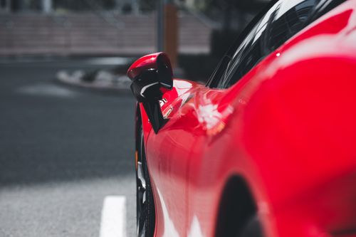 Free Close-up of a shiny red sports car with an elegant design, showcasing its smooth curves and details. Stock Photo