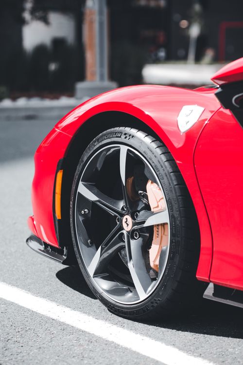 Free Detailed view of a red sports car wheel with custom rims and brake caliper on urban street. Stock Photo