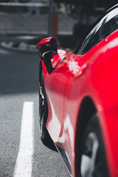 Free Detailed shot of a sleek red luxury car parked on an outdoor road. Stock Photo