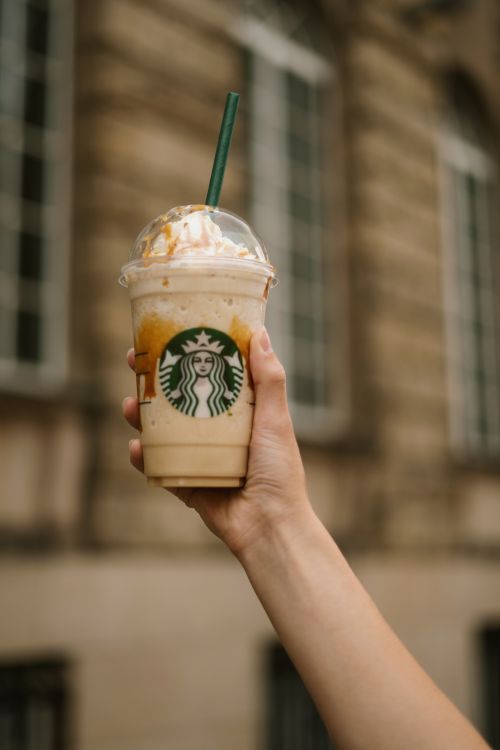 Free A hand holding a Starbucks iced frappuccino outdoors, perfect for a summer day. Stock Photo