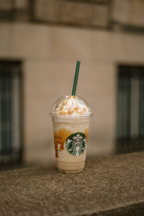 Free Delicious caramel iced coffee with whipped cream in a clear cup, shot outdoors on a ledge. Stock Photo