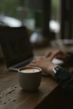 A warm, inviting workspace featuring a cup of coffee next to a laptop on a wooden table.