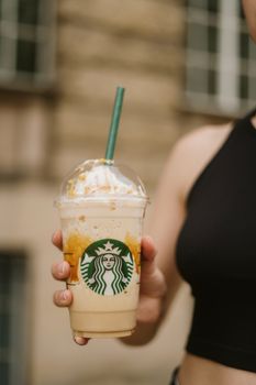 Focused shot of a hand holding a Starbucks Frappuccino outdoors.