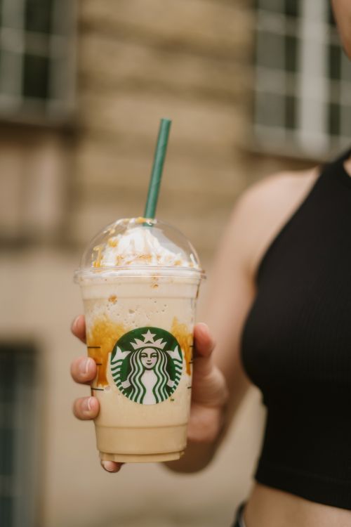 Free Focused shot of a hand holding a Starbucks Frappuccino outdoors. Stock Photo