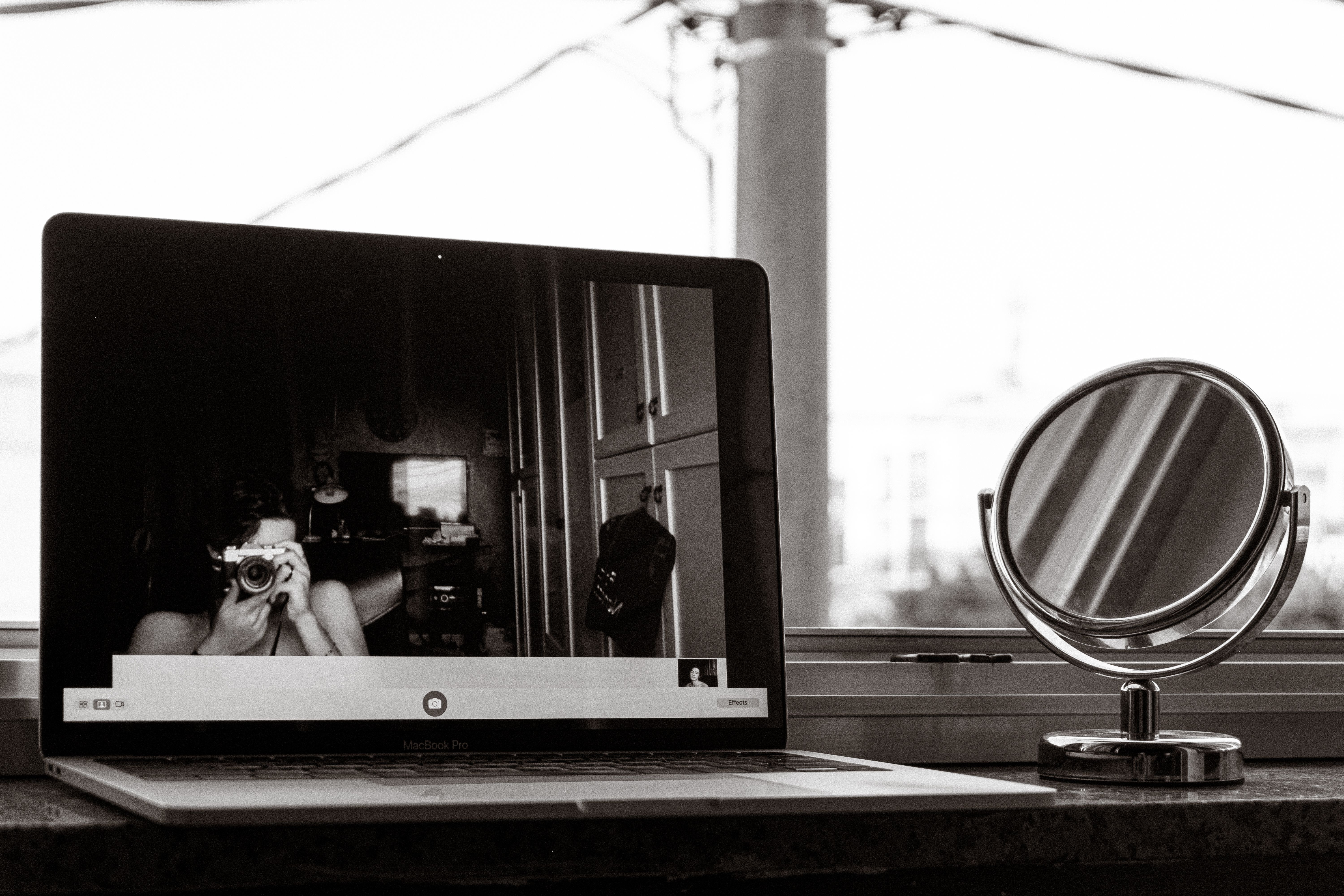 Grayscale Photo of Laptop and Round Mirror · Free Stock Photo