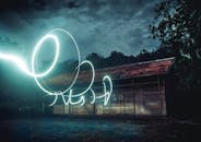 在印度尼西亚阴沉的夜空下，光线轨迹长时间照射在一间木屋上