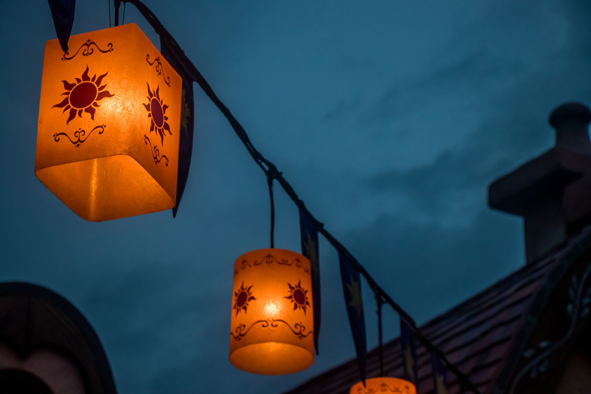 String of decorated lanterns glowing warmly against a darkening sky at dusk, creating a festive ambiance.