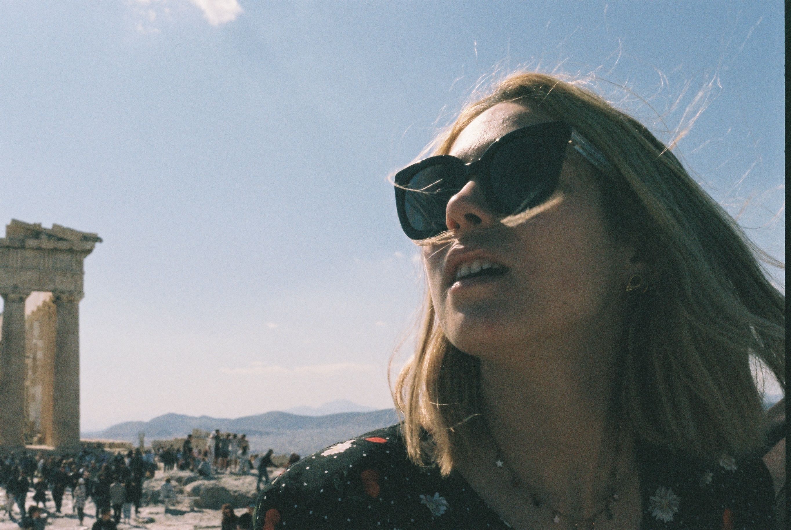 Woman in sunglasses exploring the Parthenon on a sunny day in Athens, Greece.