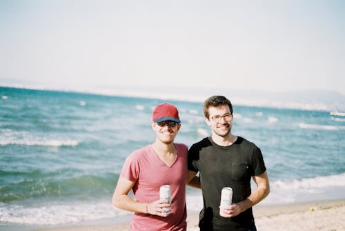 Men Holding Cans of Beer at the Beach