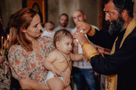 Intimate moment capturing a baby's baptism in a church with family present.