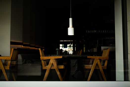 A stylish modern café interior featuring wooden chairs and a pendant lamp, creating a cozy atmosphere.