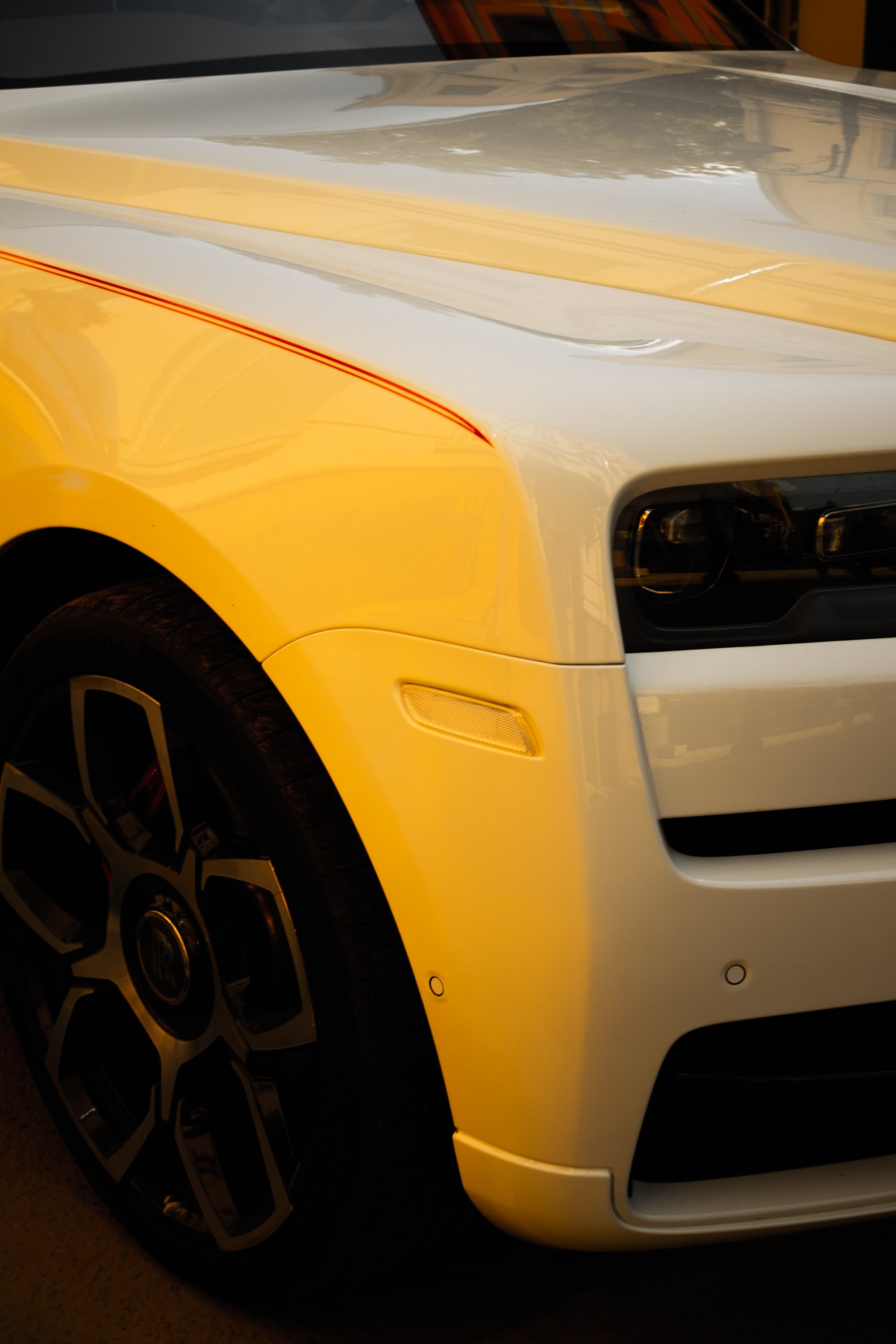 Close-up of a white luxury car's front showing sleek design and shiny surface.