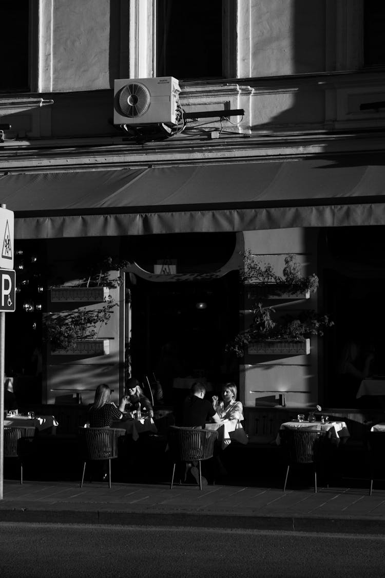 Black And White Photo Of People Sitting Outside A Restaurant