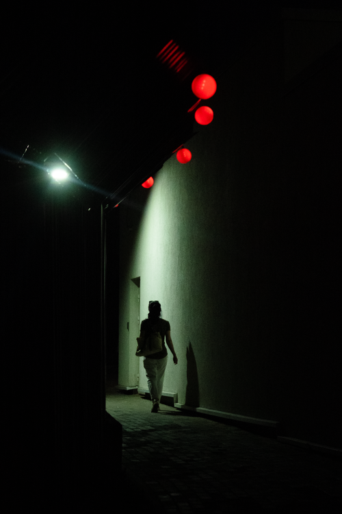 Free Silhouette of a person walking down a dimly lit alley with red lanterns glowing. Stock Photo