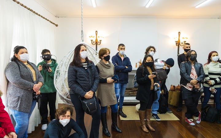 A group of adults indoors, wearing facemasks, attending a meeting or gathering.