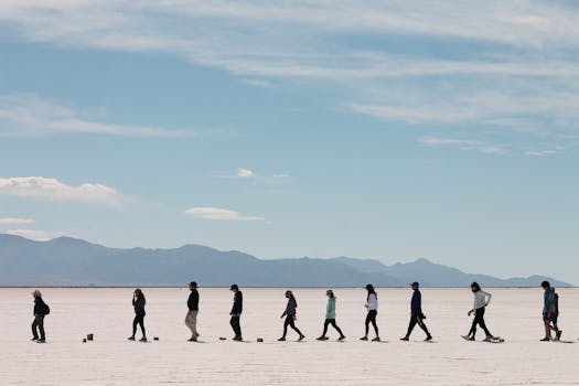 A group of people walking across the vast Salinas Grandes salt flats in Jujuy, Argentina.
