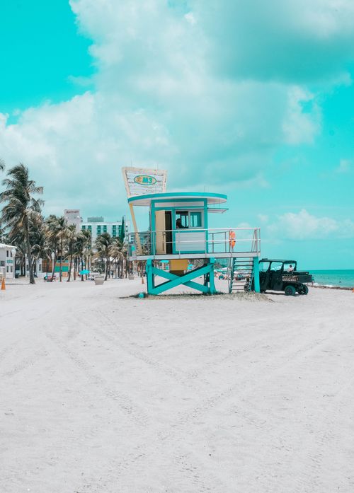 Free Colorful lifeguard tower on a sandy tropical beach. Clear skies and palm trees enhance the coastal vibe. Stock Photo