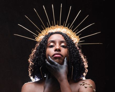 Woman with Curly Hair in a Headpiece with her Hand on her Face