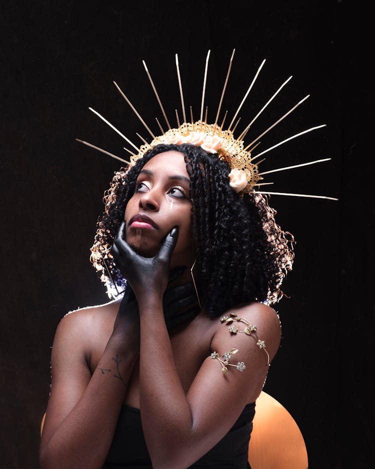 Woman In A Headpiece With Her Face In Her Painted Hands