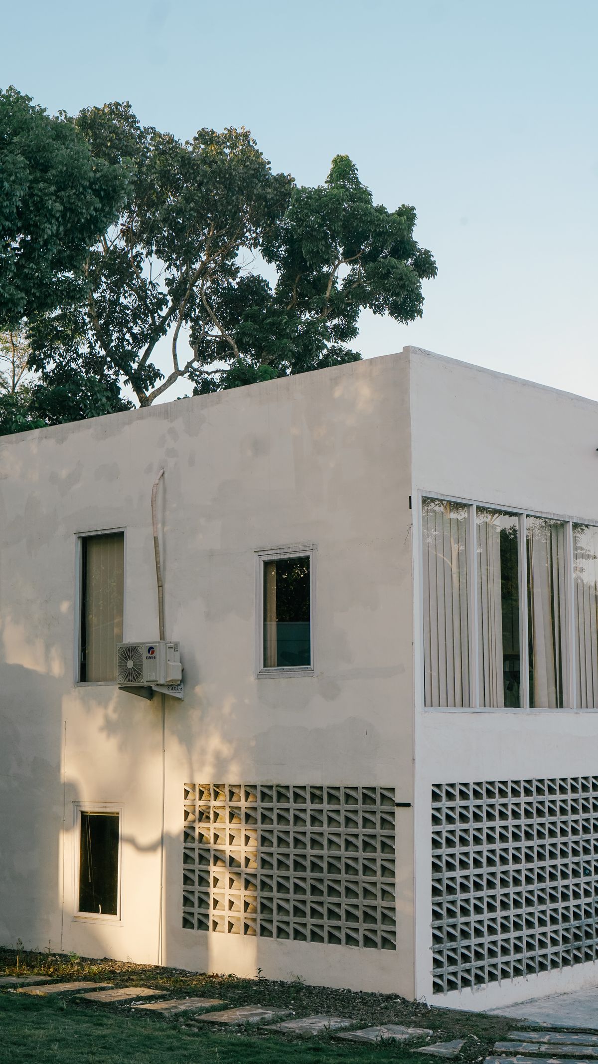 Casa blanca de dos niveles con celosías junto a árboles